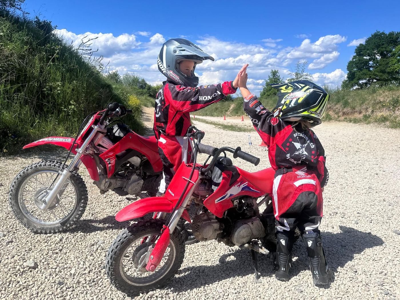 Motocross Gutschein als Geschenk: zwei Kinder geben sich auf ihren Kinderbikes ein High Five